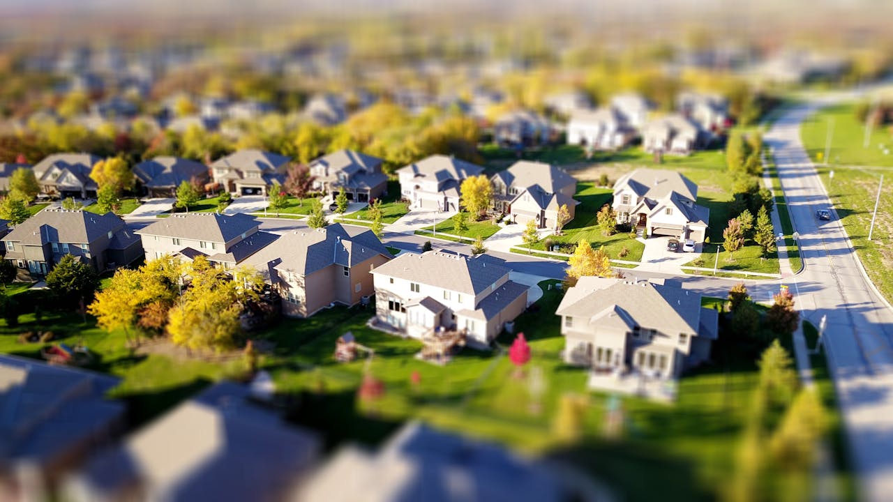 our-services-2 Tilt-shift aerial photo of a suburban neighborhood with green lawns and roads.